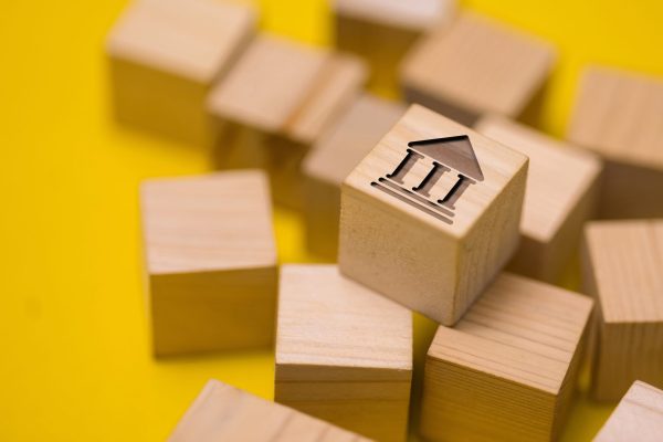 Wooden,Block,With,Bank,Building,Icon,On,Yellow,Background,,Representing