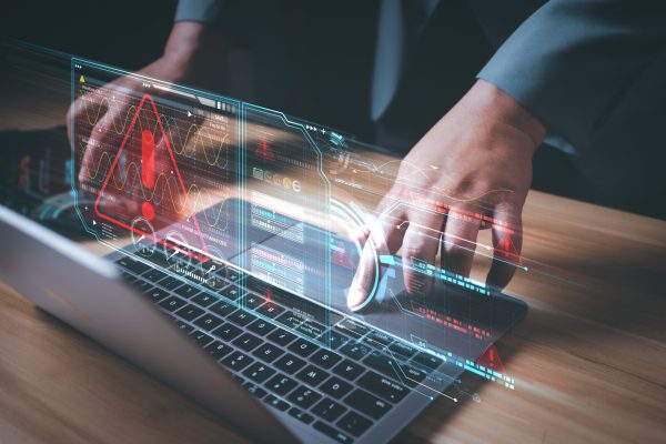 Hacker,Or,Programmer,Using,Laptop,With,Triangle,Caution,Warning,Sign,